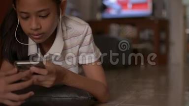 亚洲可爱的女孩躺在地板上，在家里用手机社交。 女少年看<strong>音乐视频</strong>..